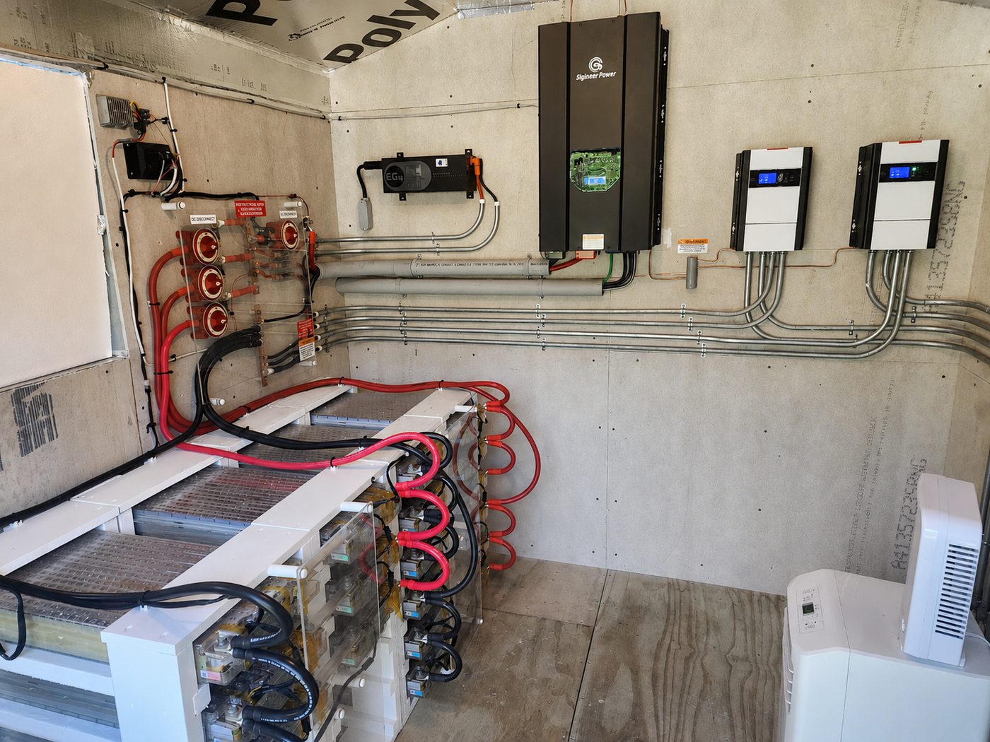Off-grid power room with battery banks, disconnects, and wall-mounted inverters